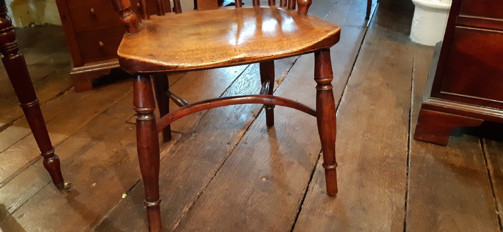 An antique yew wood childs Windsor armchair featuring a hoop back with central pierced splat, spindled backrest, shaped armrests, turned legs, and a carved seat. View III