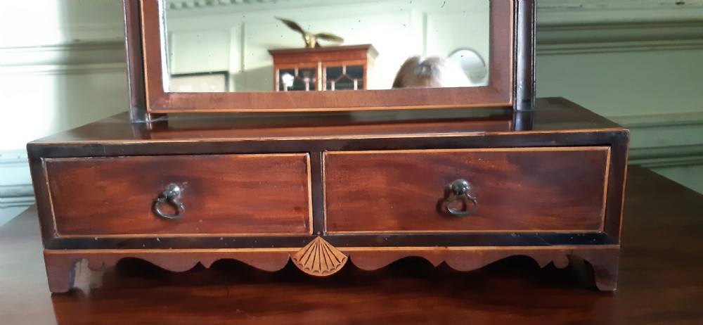 An antique Regency mahogany toilet mirror featuring an arched tilting mirror frame mounted on uprights over a two-drawer base with shell inlay. View III