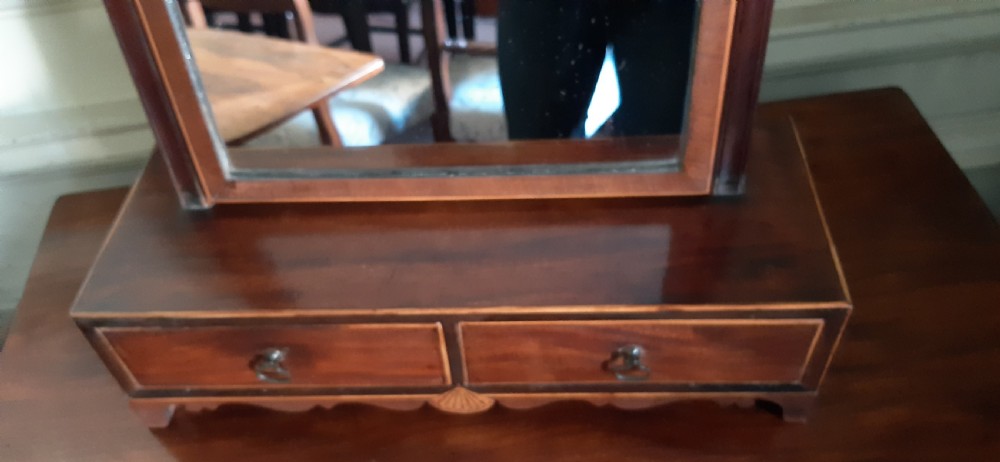 An antique Regency mahogany toilet mirror featuring an arched tilting mirror frame mounted on uprights over a two-drawer base with shell inlay. View IV