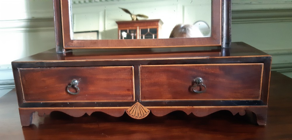 An antique Regency mahogany toilet mirror featuring an arched tilting mirror frame mounted on uprights over a two-drawer base with shell inlay. View VIII