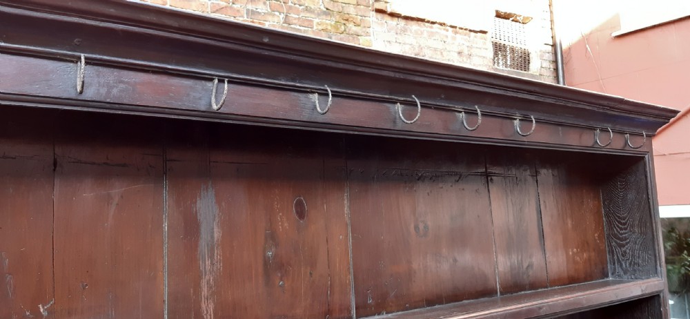 A dark oak antique dresser featuring an open plate rack with three shelves above three frieze drawers, supported by turned pillars over an open potboard base. View XVIII