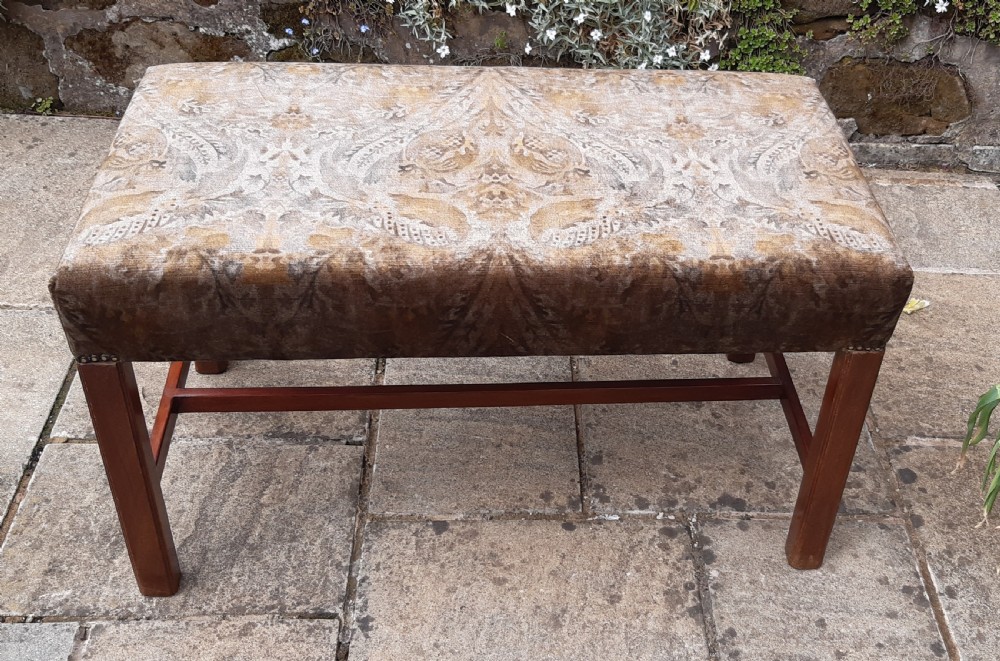 An upholstered rectangular mahogany stool featuring patterned brown fabric with stud detailing and straight legs joined by an H-stretcher. View III