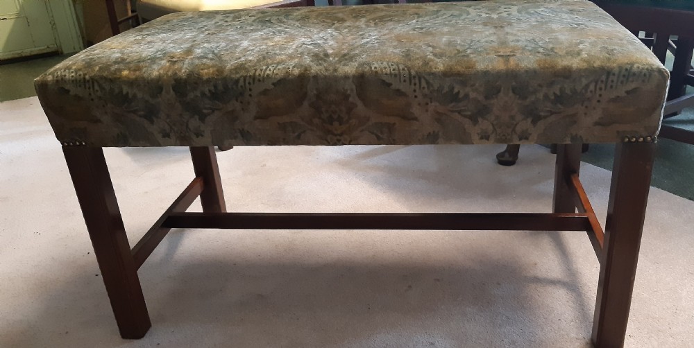An upholstered rectangular mahogany stool featuring patterned brown fabric with stud detailing and straight legs joined by an H-stretcher. View V