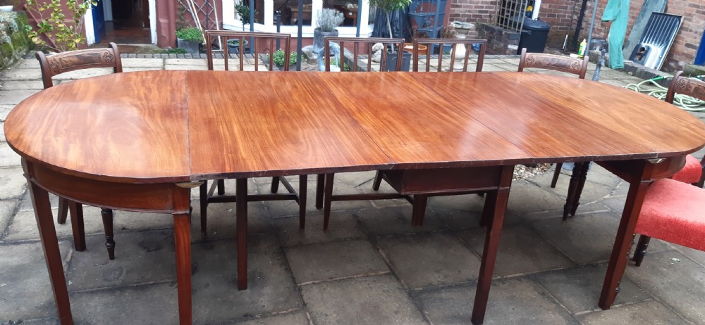 A large Georgian mahogany extending dining table featuring modular leaves and square tapered legs.