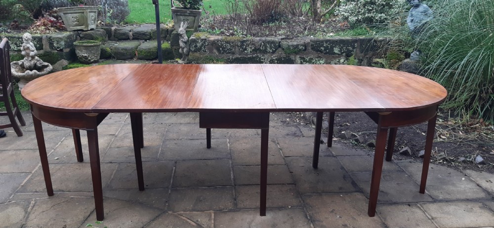 A large Georgian mahogany extending dining table featuring modular leaves and square tapered legs. View IV