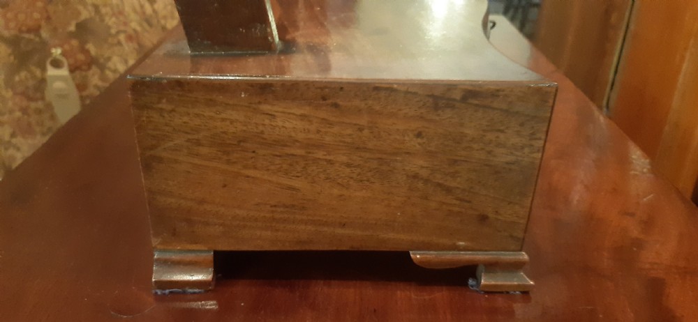 An antique mahogany toilet mirror featuring a shield-shaped swivelling frame set on curved uprights above a serpentine-front base with small drawers. View IV