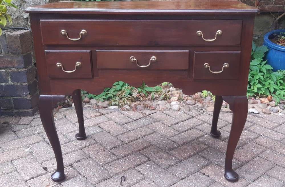 An Early Georgian mahogany lowboy featuring one wide upper drawer above three smaller drawers, brass swan-neck handles, a shaped lower apron, and cabriole legs with pad feet. View III