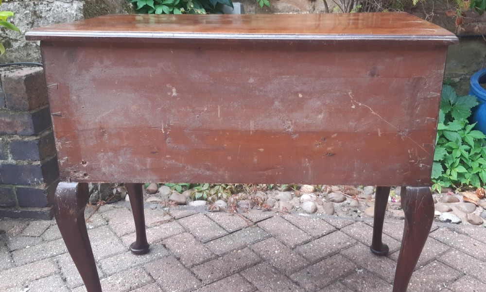 An Early Georgian mahogany lowboy featuring one wide upper drawer above three smaller drawers, brass swan-neck handles, a shaped lower apron, and cabriole legs with pad feet. View VIII