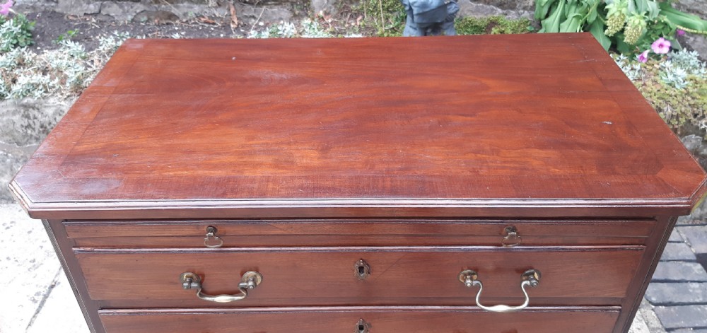 A small Georgian mahogany chest of drawers featuring four graduated drawers with brass handles, a pull-out brushing slide, canted reeded corners, and bracket feet. View III