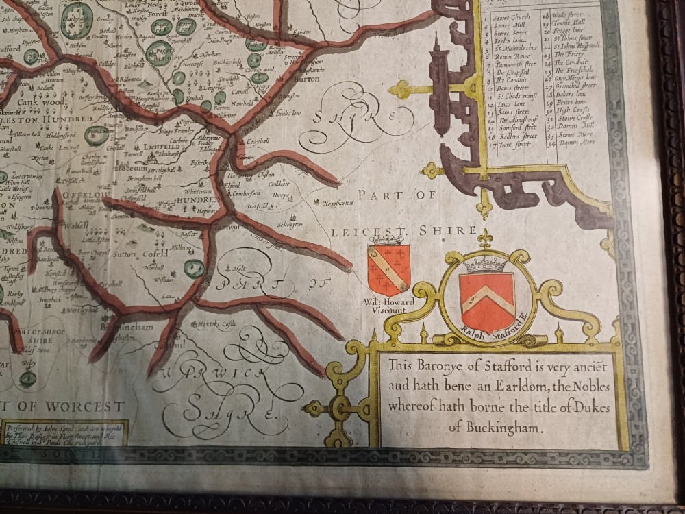 Framed 17th-century hand-coloured engraved map of Staffordshire by John Speed featuring heraldic crests and inset town plans of Stafford and Lichfield. View VI