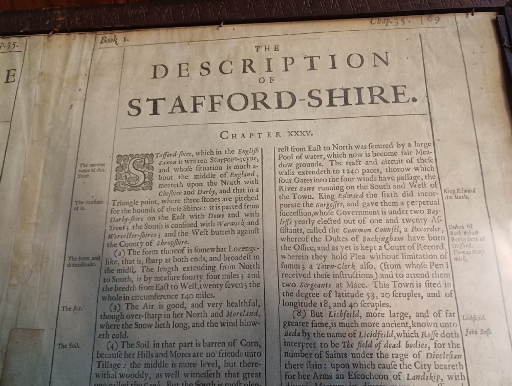 Framed 17th-century hand-coloured engraved map of Staffordshire by John Speed featuring heraldic crests and inset town plans of Stafford and Lichfield. View IX