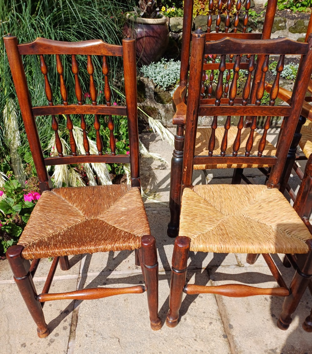 A set of six dark oak spindleback dining chairs featuring hand-woven rush seats and turned wooden legs. View II