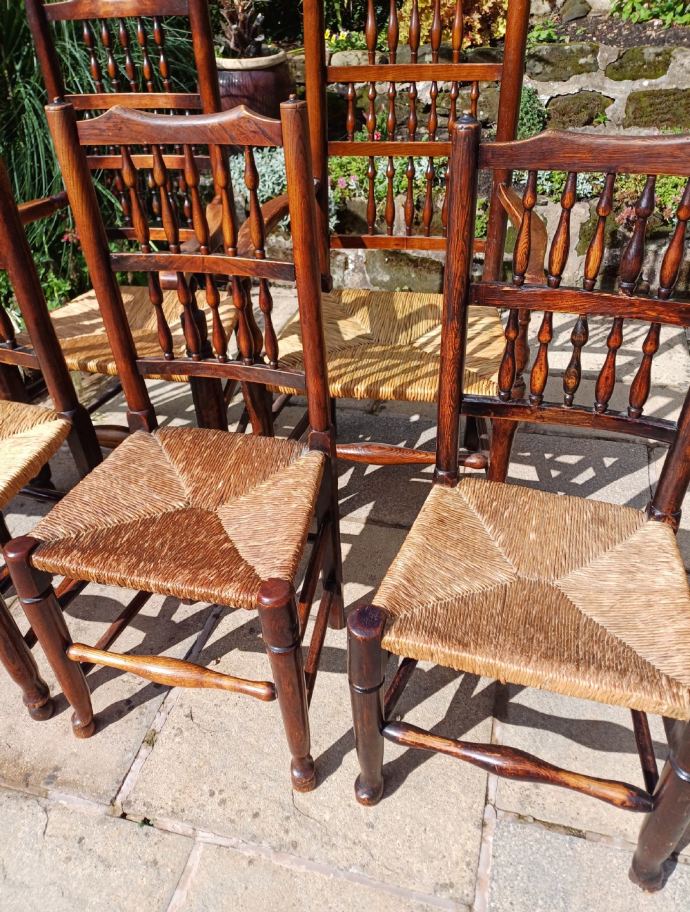 A set of six dark oak spindleback dining chairs featuring hand-woven rush seats and turned wooden legs. View III