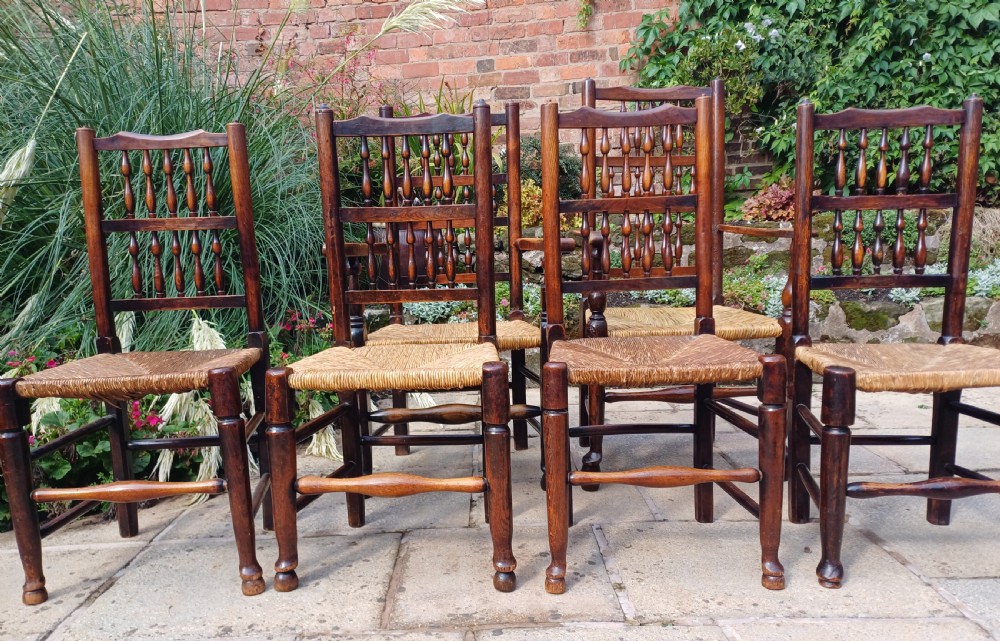 A set of six dark oak spindleback dining chairs featuring hand-woven rush seats and turned wooden legs. View IV