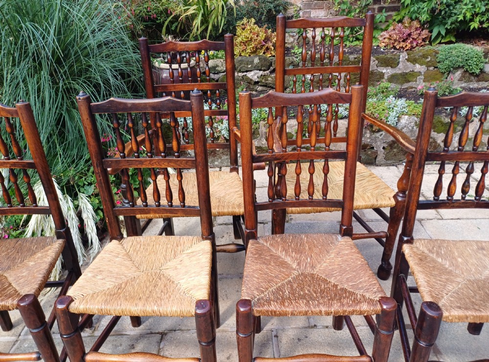 A set of six dark oak spindleback dining chairs featuring hand-woven rush seats and turned wooden legs. View V