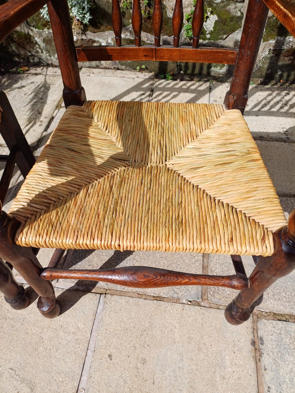 A set of six dark oak spindleback dining chairs featuring hand-woven rush seats and turned wooden legs. View VI