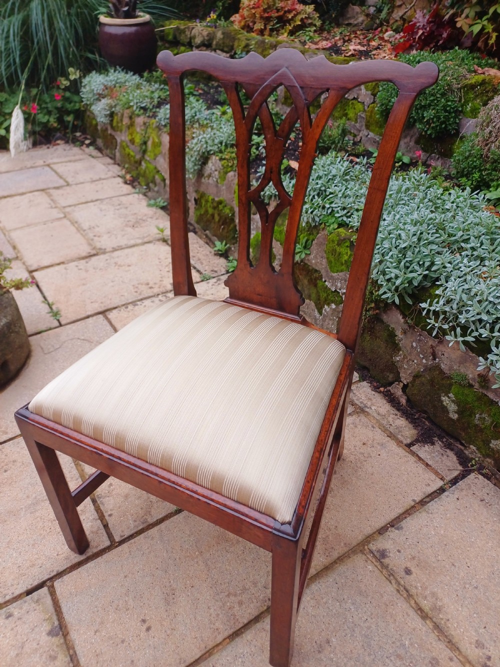 An 18th-century Chippendale mahogany side chair featuring a carved Gothic pierced splat back and a neutral striped fabric seat.
