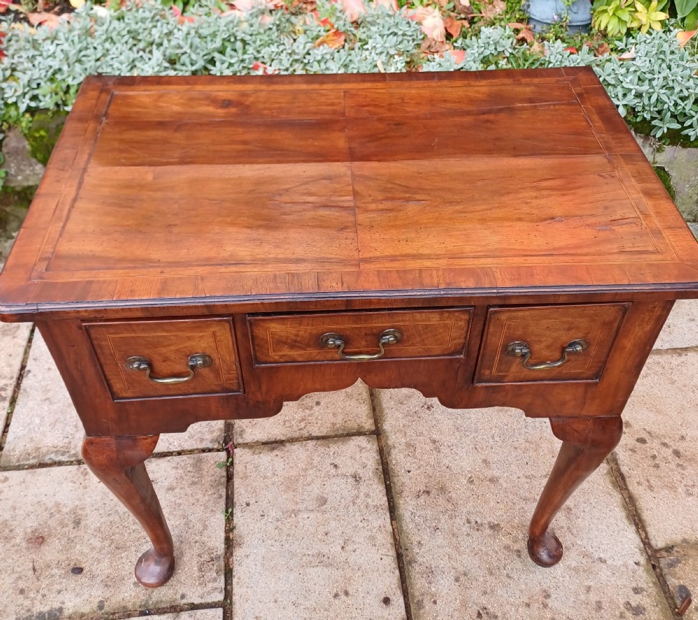 A Georgian walnut lowboy table featuring three front drawers with brass swan-neck handles, a shaped apron, and four cabriole legs ending in pad feet. View II