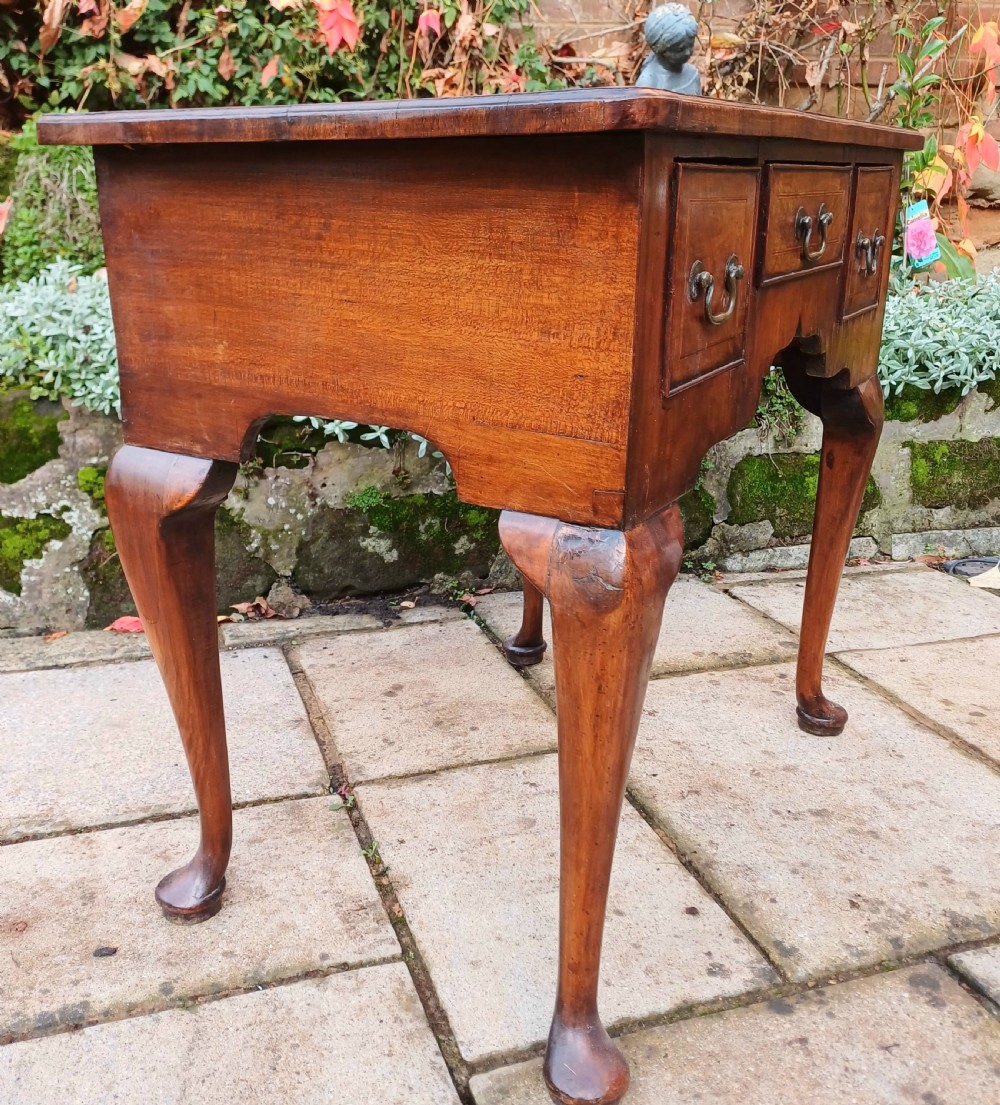 A Georgian walnut lowboy table featuring three front drawers with brass swan-neck handles, a shaped apron, and four cabriole legs ending in pad feet. View III