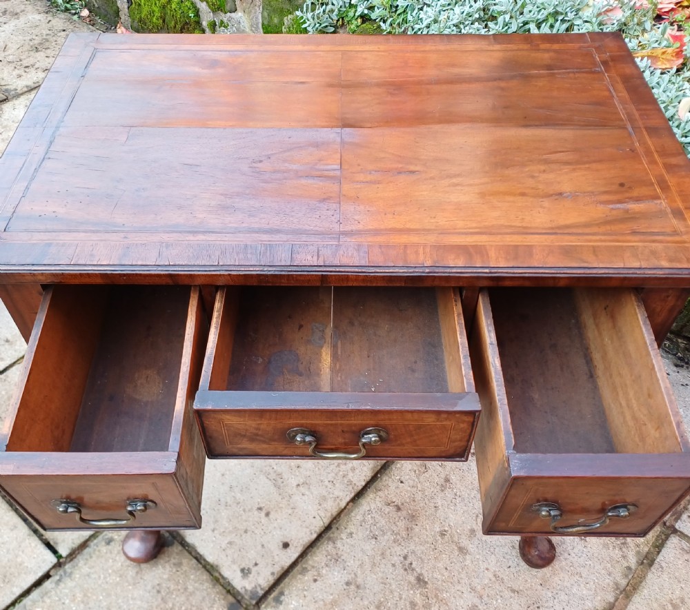 A Georgian walnut lowboy table featuring three front drawers with brass swan-neck handles, a shaped apron, and four cabriole legs ending in pad feet. View IV