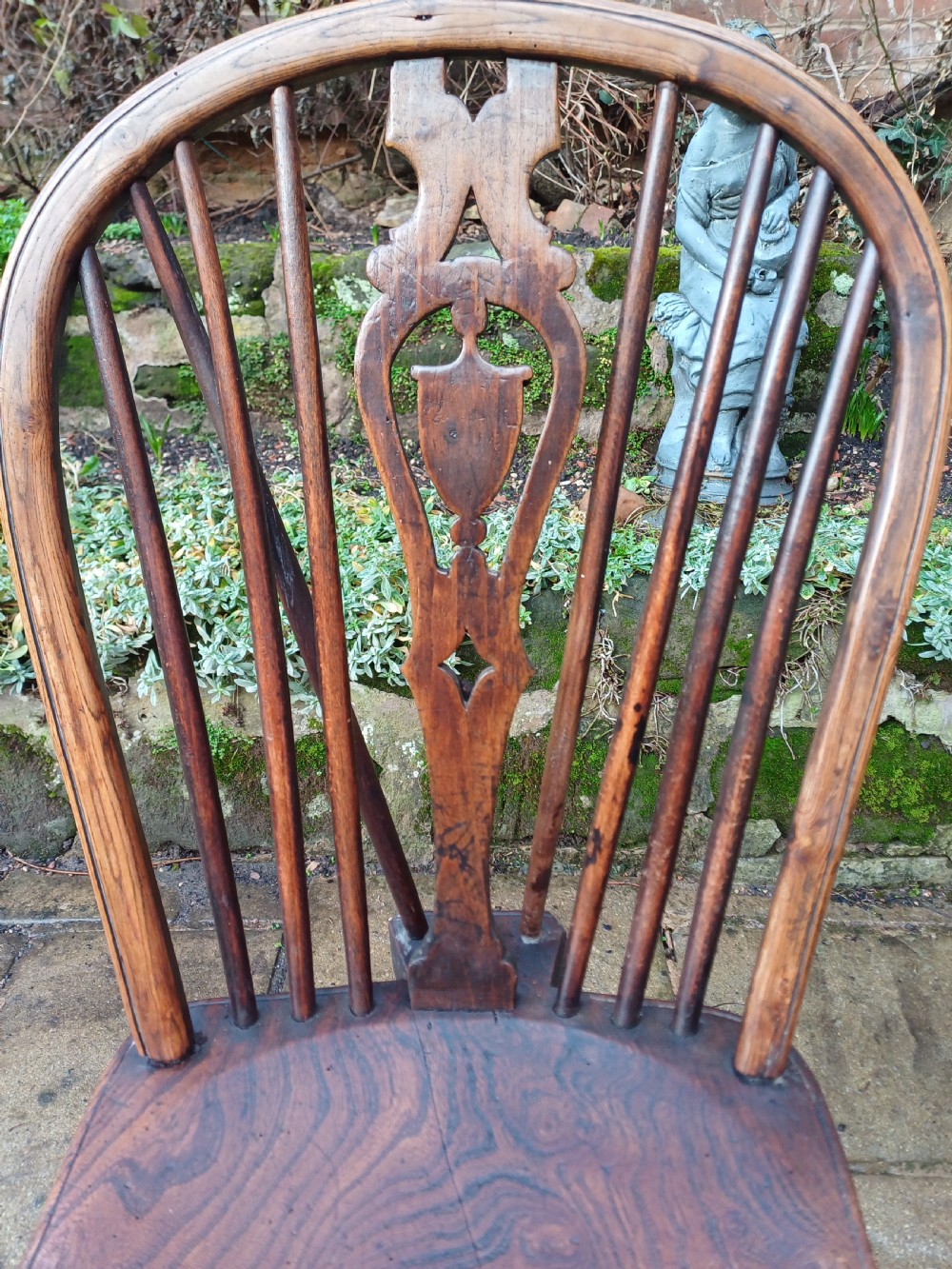 An early nineteenth-century wooden wheelback Windsor chair featuring a contoured elm saddle seat, pierced wheel splat, arched hoop back, and turned legs. View II