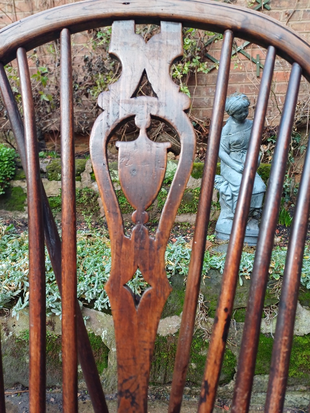 An early nineteenth-century wooden wheelback Windsor chair featuring a contoured elm saddle seat, pierced wheel splat, arched hoop back, and turned legs. View III