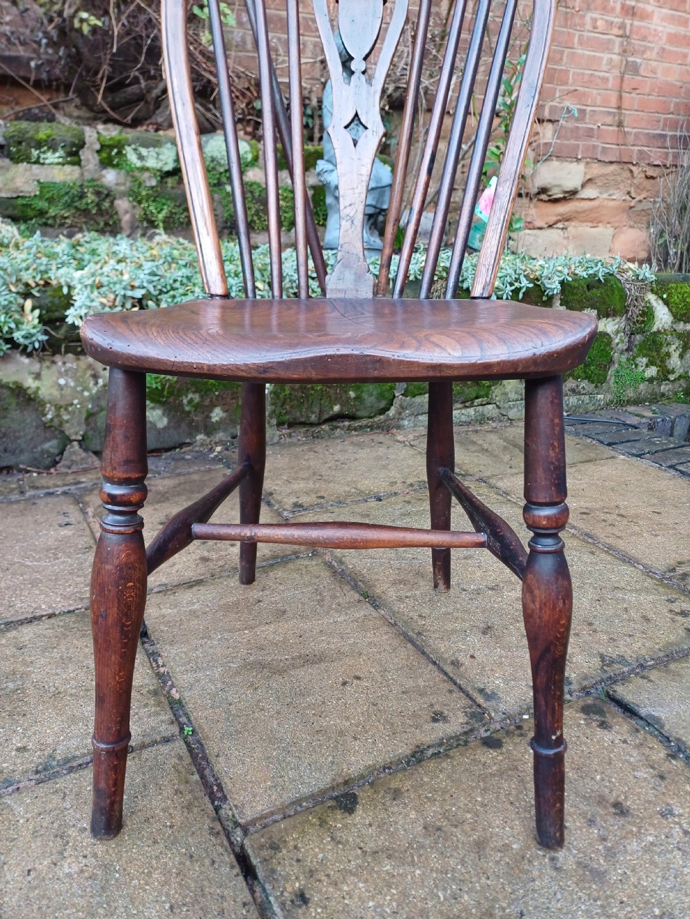 An early nineteenth-century wooden wheelback Windsor chair featuring a contoured elm saddle seat, pierced wheel splat, arched hoop back, and turned legs. View VI
