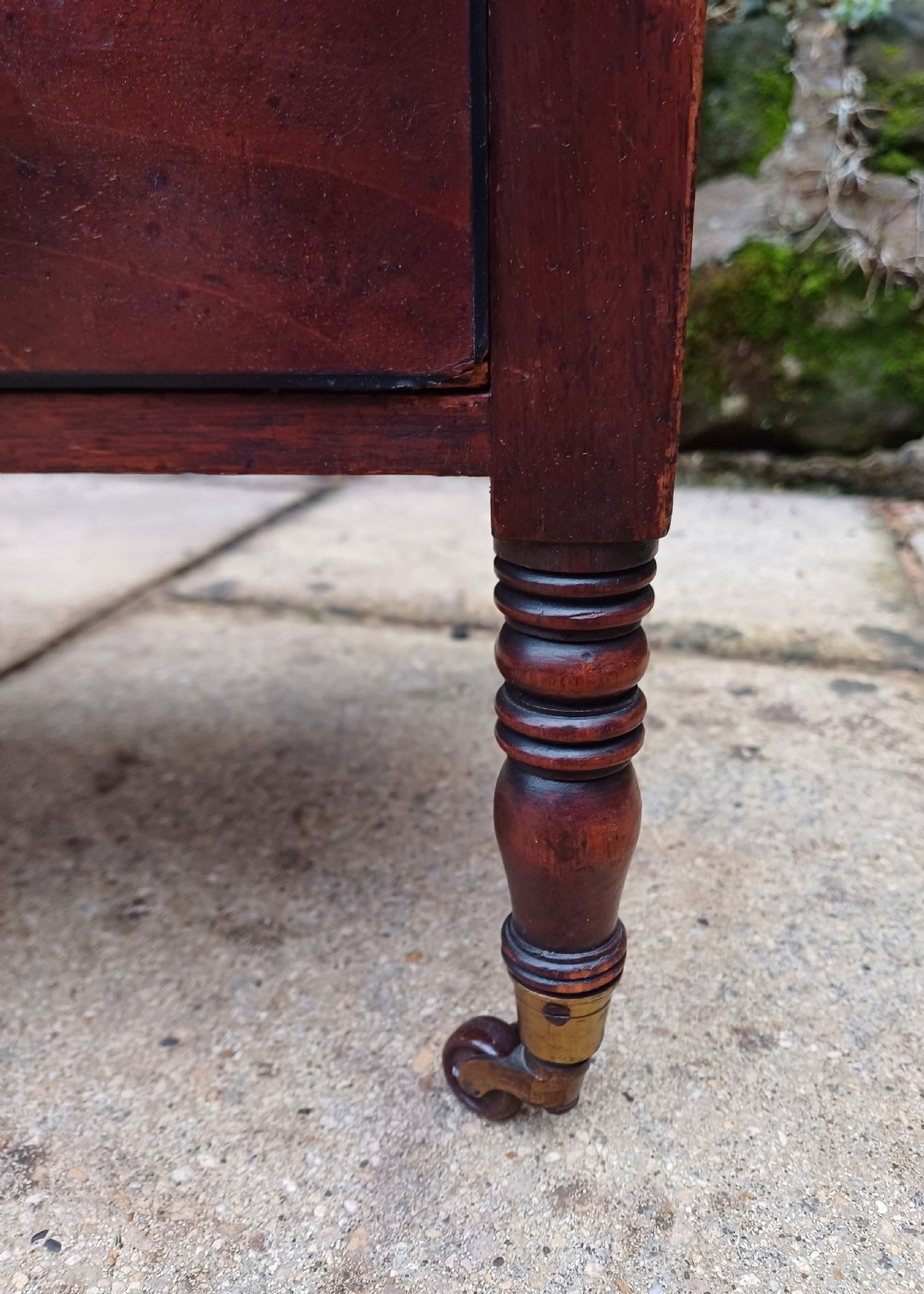 A Regency mahogany music canterbury featuring curved slatted divisions, a base drawer with two brass knobs, turned legs, and brass castors. View VI