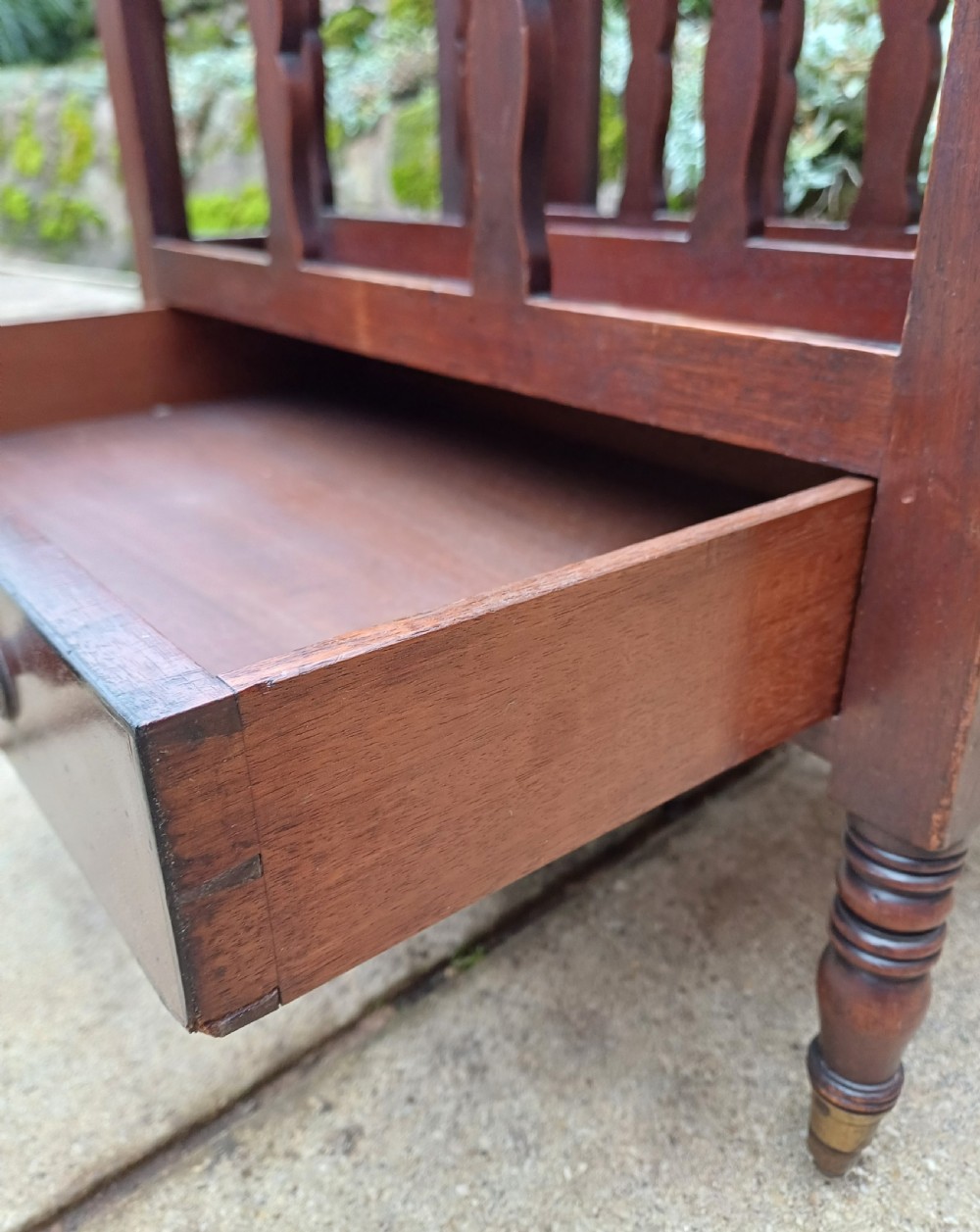 A Regency mahogany music canterbury featuring curved slatted divisions, a base drawer with two brass knobs, turned legs, and brass castors. View VIII