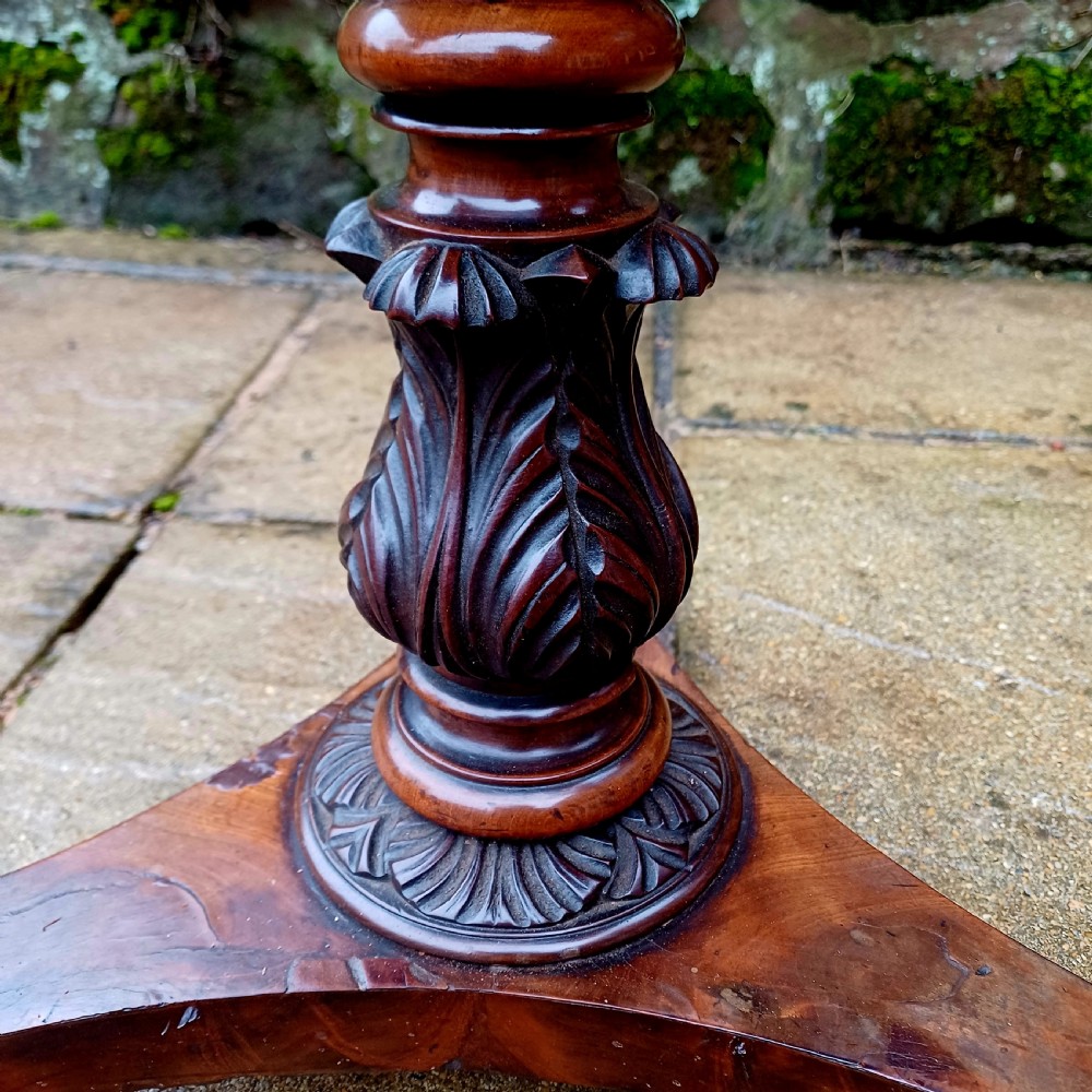 A Victorian flame mahogany work table featuring a shaped top with a central keyhole escutcheon, supported by C-scroll arms, a carved acanthus pedestal, and a triform base with claw feet. View IV
