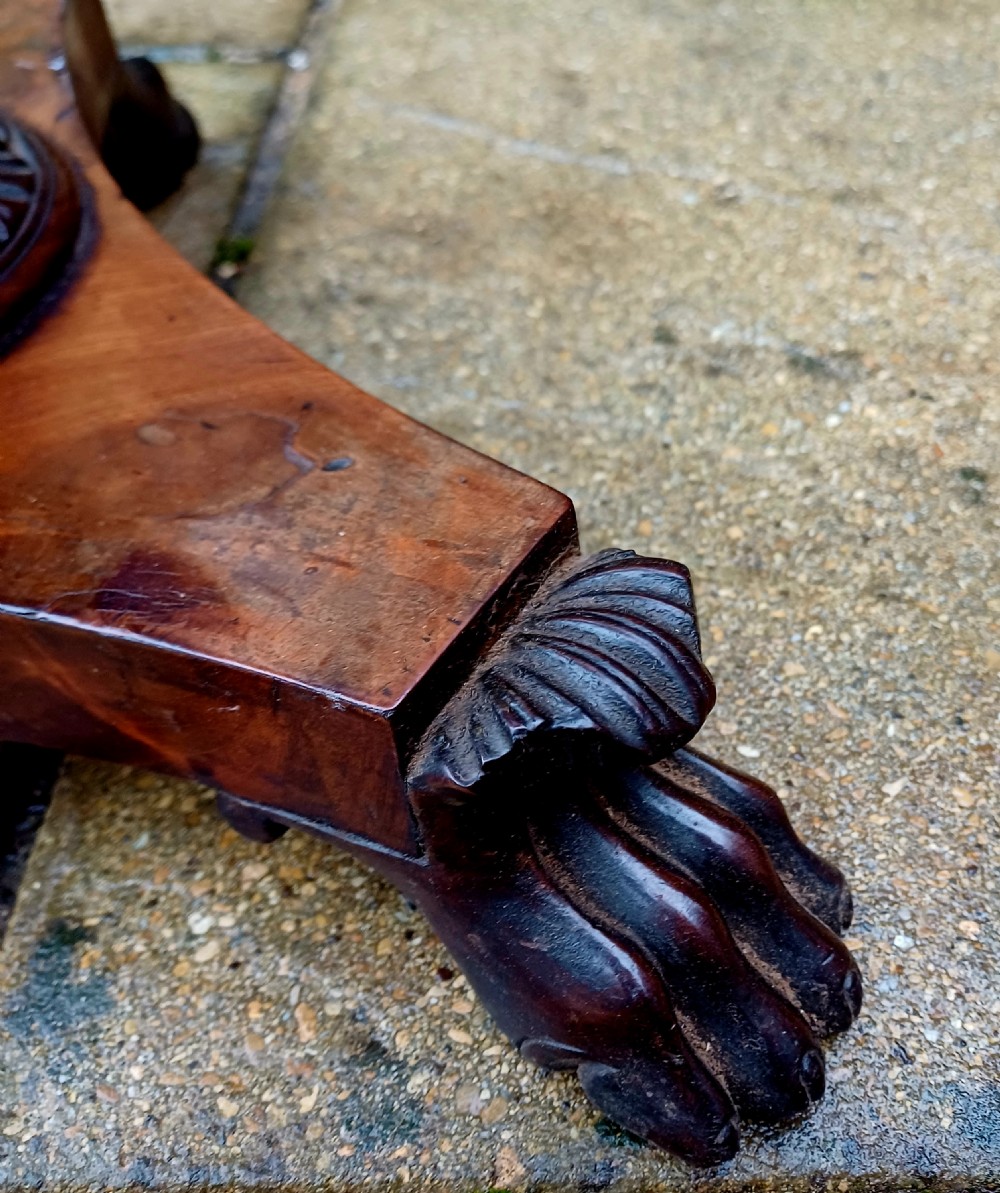 A Victorian flame mahogany work table featuring a shaped top with a central keyhole escutcheon, supported by C-scroll arms, a carved acanthus pedestal, and a triform base with claw feet. View XI