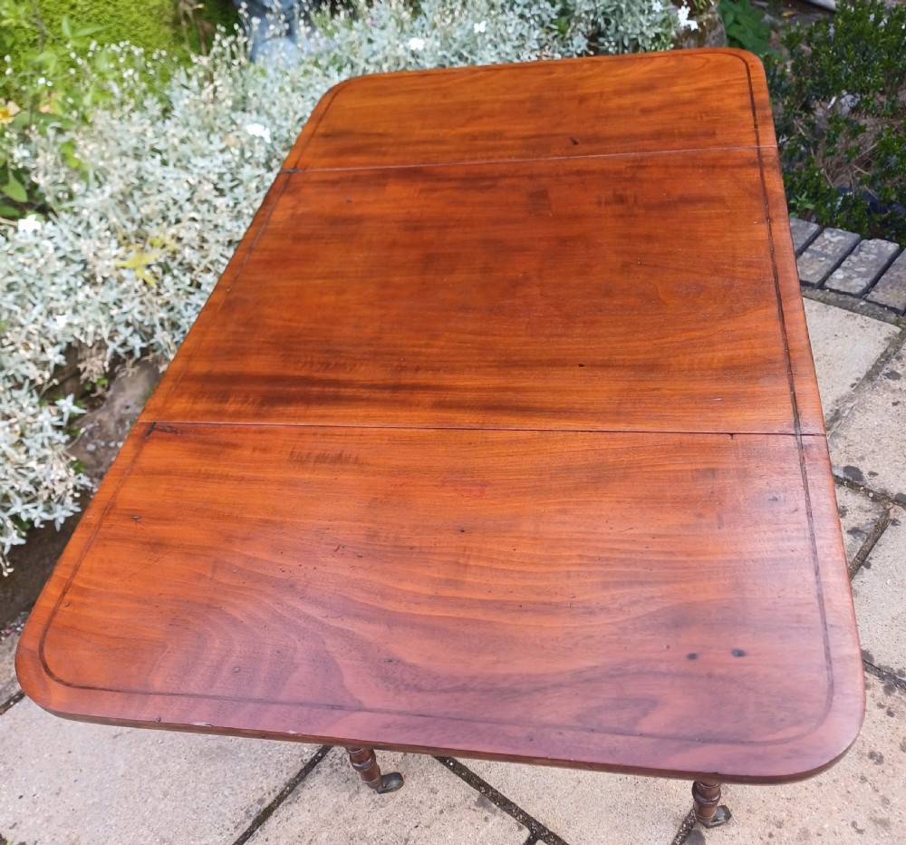 A Regency mahogany Pembroke work table featuring two drop-leaf flaps, three drawer fronts with brass knobs and keyholes, set on turned legs with castors. View XII