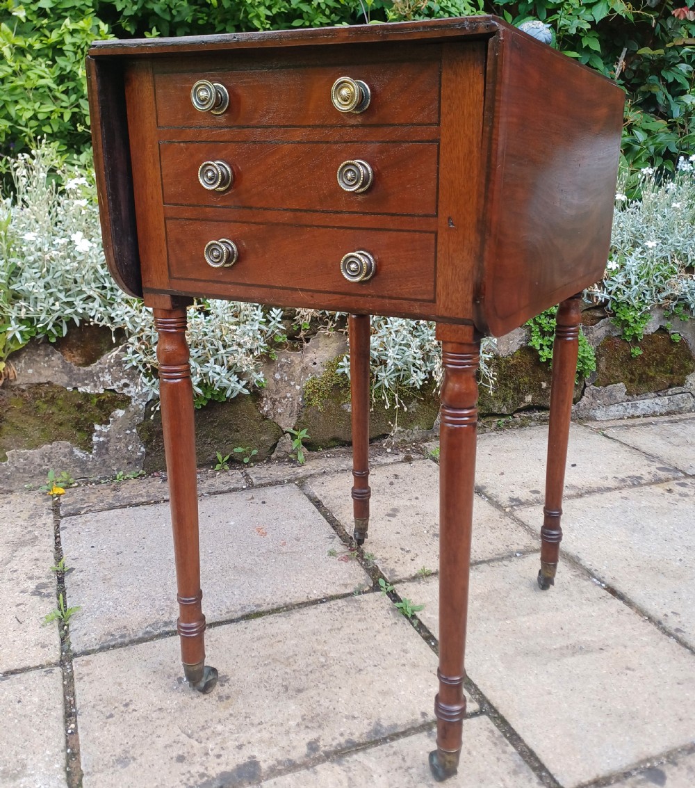 A Regency mahogany Pembroke work table featuring two drop-leaf flaps, three drawer fronts with brass knobs and keyholes, set on turned legs with castors. View XIII