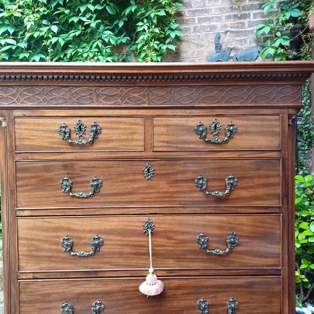 An 18th-century Georgian mahogany tallboy chest on chest featuring a carved frieze, brass handles, and multiple graduated drawers. View X