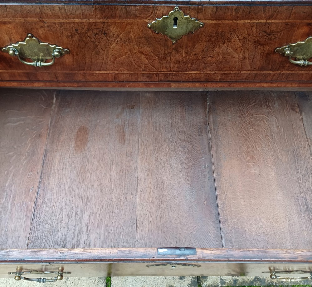 An early 18th-century walnut chest on chest featuring multiple tiered drawers, crossbanded inlay, brass drop handles, and bracket feet. View VIII
