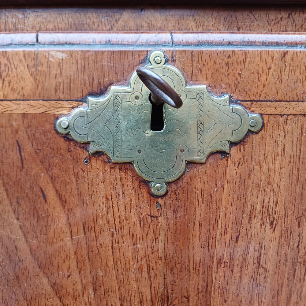 An early 18th-century walnut chest on chest featuring multiple tiered drawers, crossbanded inlay, brass drop handles, and bracket feet. View IX