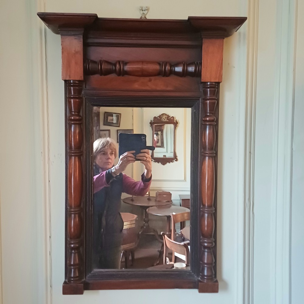 A 19th-century rectangular mahogany wall pier mirror with an architectural corniced top, decorative turned columns, and central spindle details.