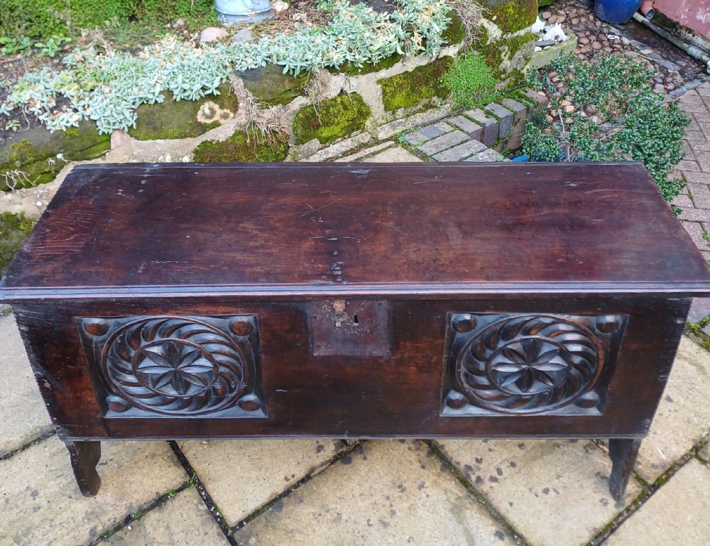 A 17th-century dark oak coffer featuring two carved rosette front panels, an iron lock plate, and a flat hinged lid. View II