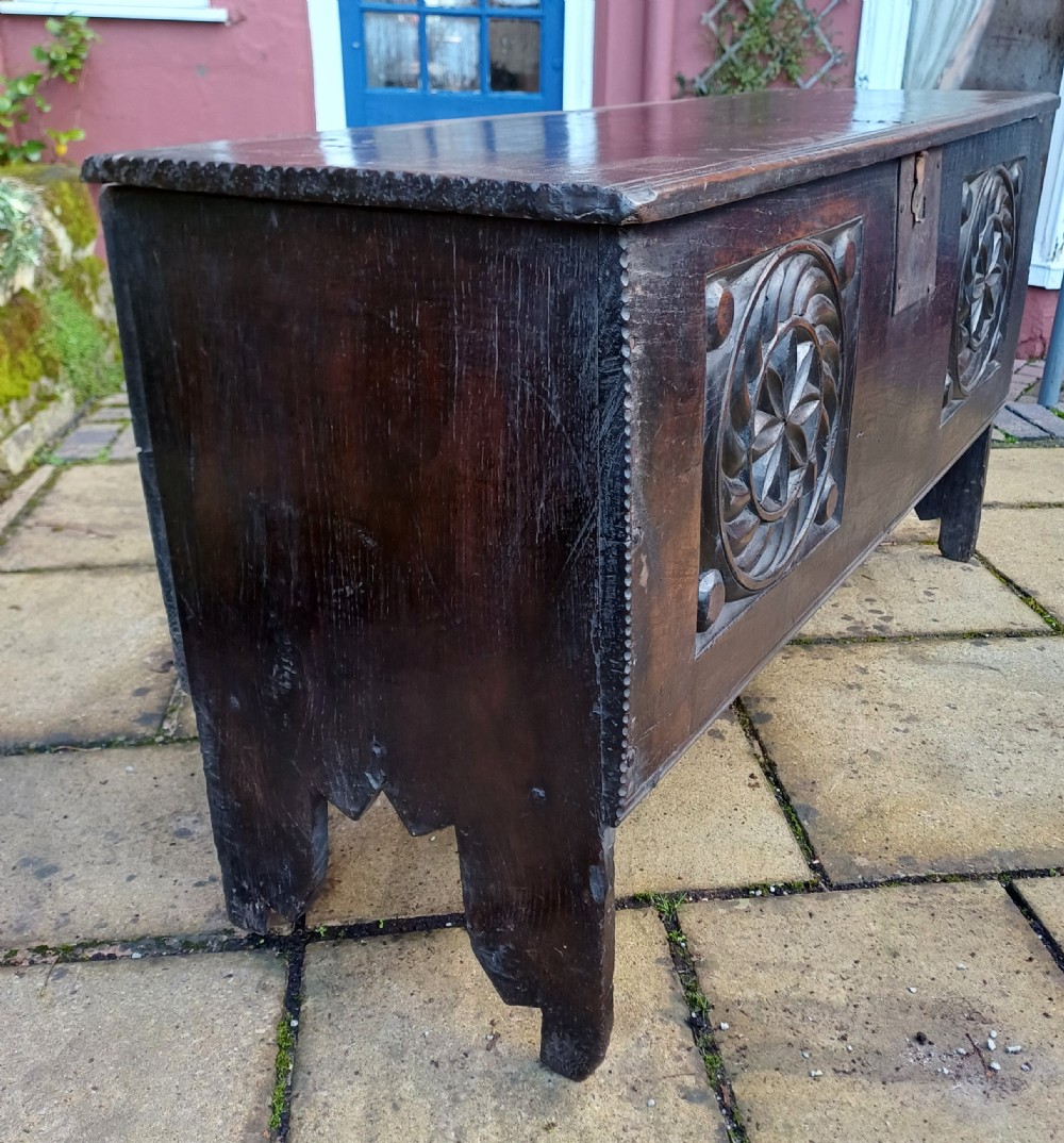 A 17th-century dark oak coffer featuring two carved rosette front panels, an iron lock plate, and a flat hinged lid. View III