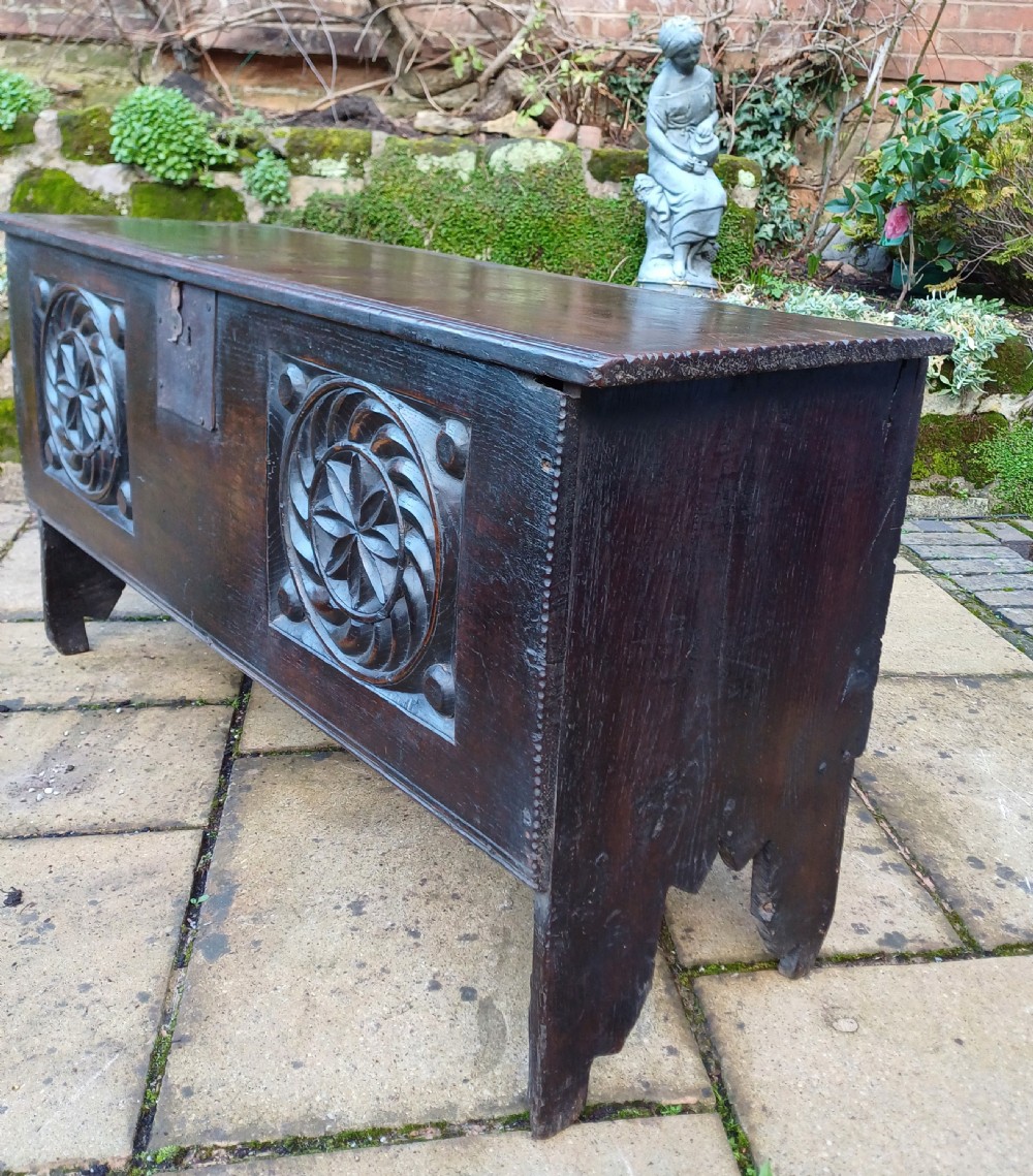 A 17th-century dark oak coffer featuring two carved rosette front panels, an iron lock plate, and a flat hinged lid. View VI
