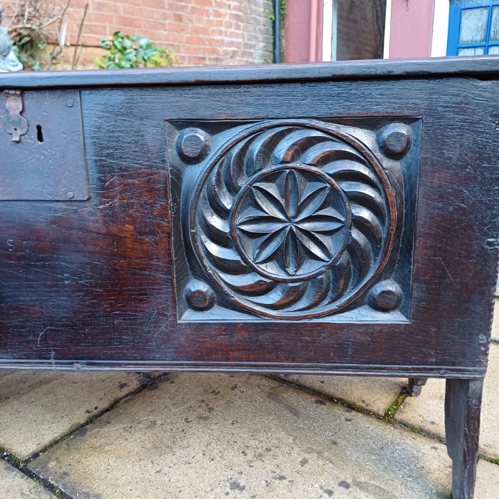 A 17th-century dark oak coffer featuring two carved rosette front panels, an iron lock plate, and a flat hinged lid. View VII
