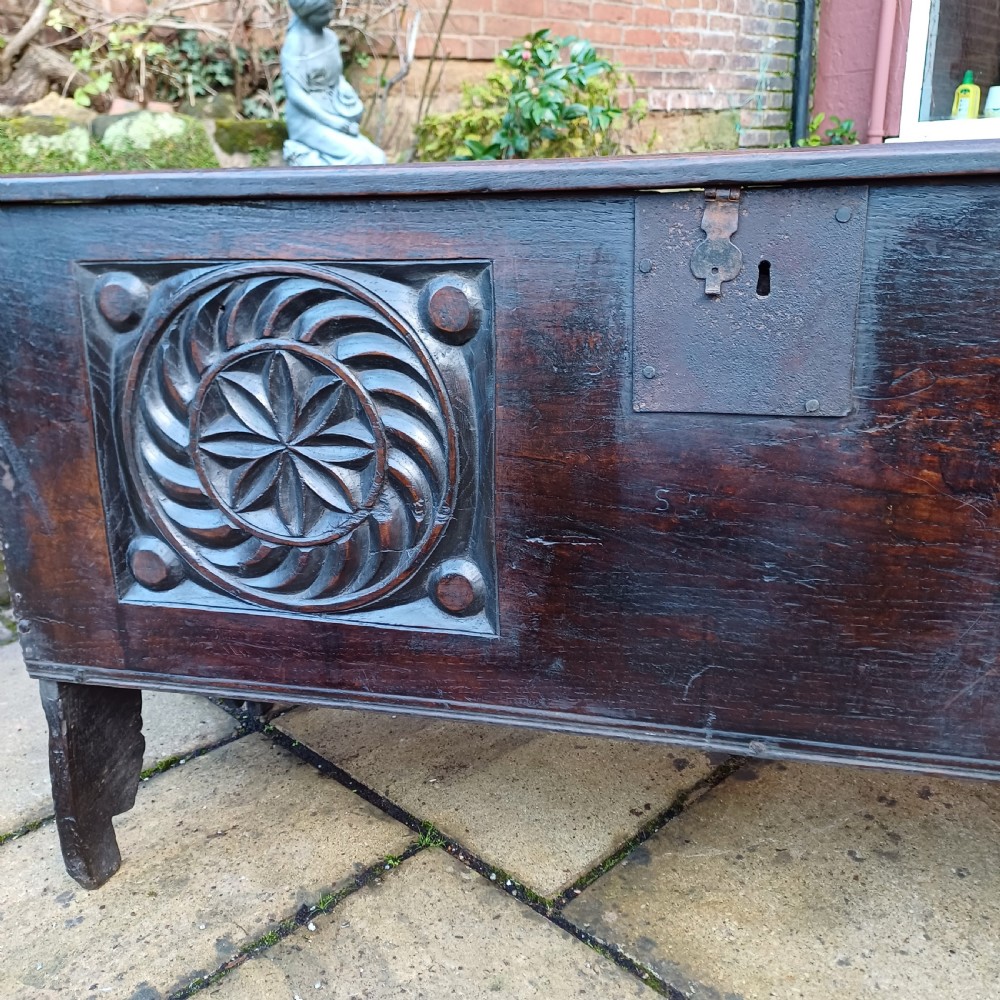 A 17th-century dark oak coffer featuring two carved rosette front panels, an iron lock plate, and a flat hinged lid. View VIII
