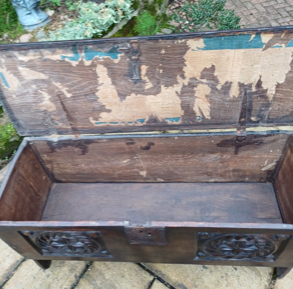 A 17th-century dark oak coffer featuring two carved rosette front panels, an iron lock plate, and a flat hinged lid. View IX
