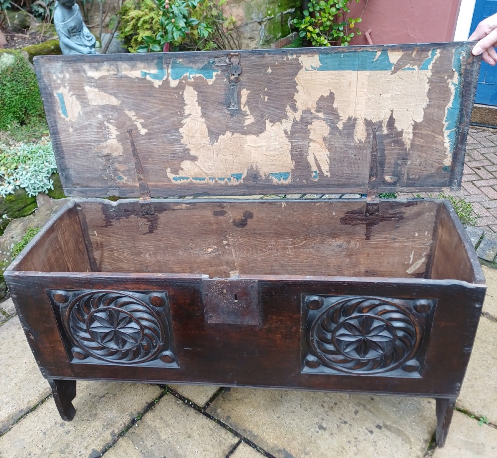 A 17th-century dark oak coffer featuring two carved rosette front panels, an iron lock plate, and a flat hinged lid. View X