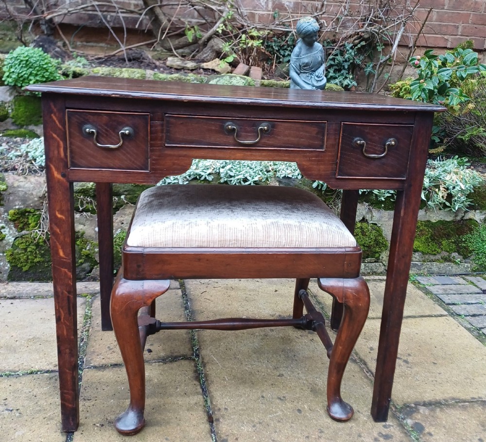 A Georgian dark oak lowboy side table featuring three drawers with brass swan-neck handles, a shaped apron, and four straight legs. View VIII