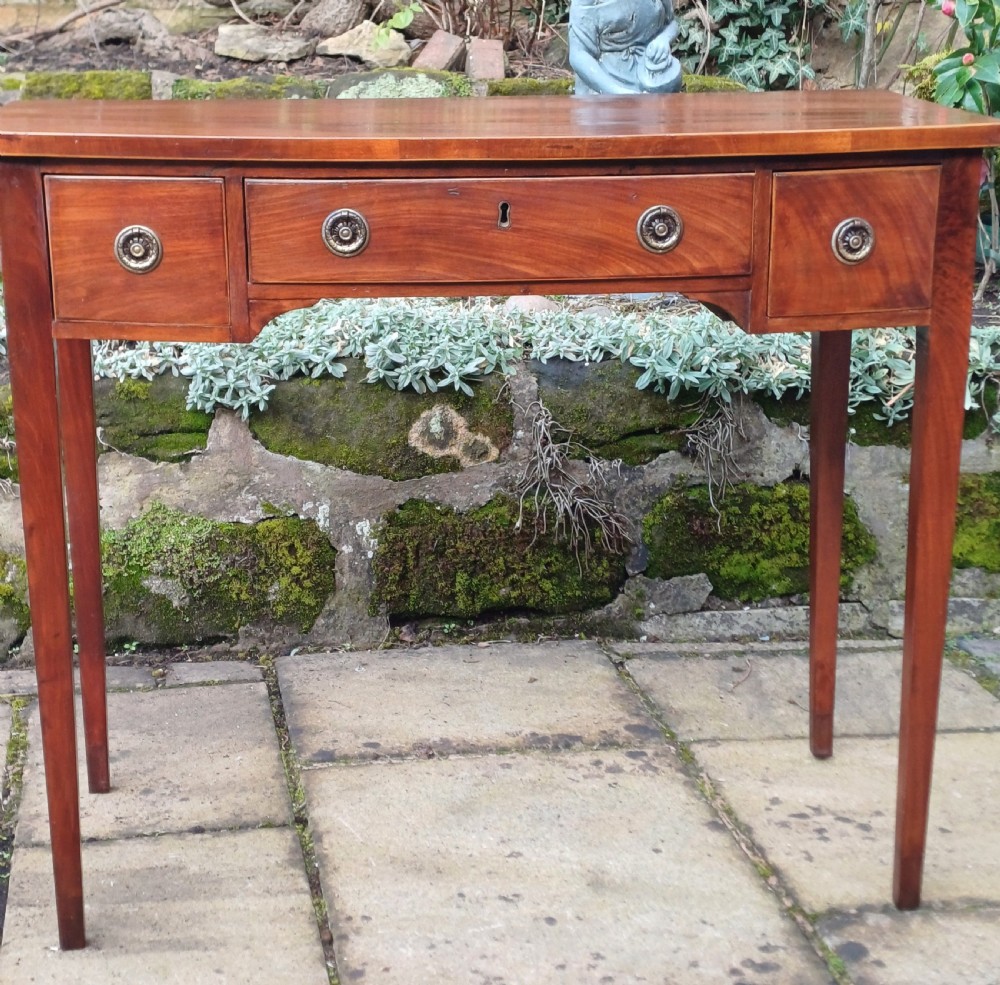 A nineteenth-century mahogany writing table featuring a central drawer flanked by two side drawers with brass ring handles, supported on slim tapered legs. View III