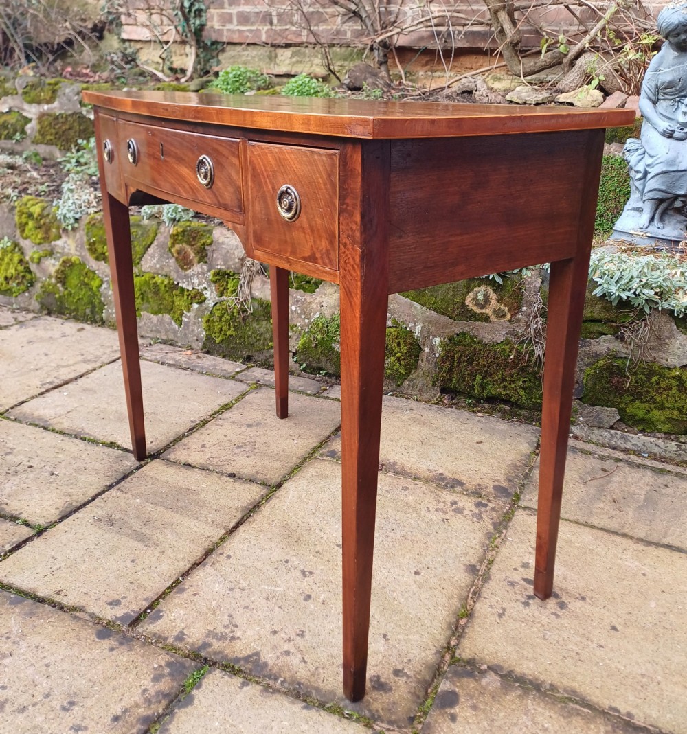 A nineteenth-century mahogany writing table featuring a central drawer flanked by two side drawers with brass ring handles, supported on slim tapered legs. View VII