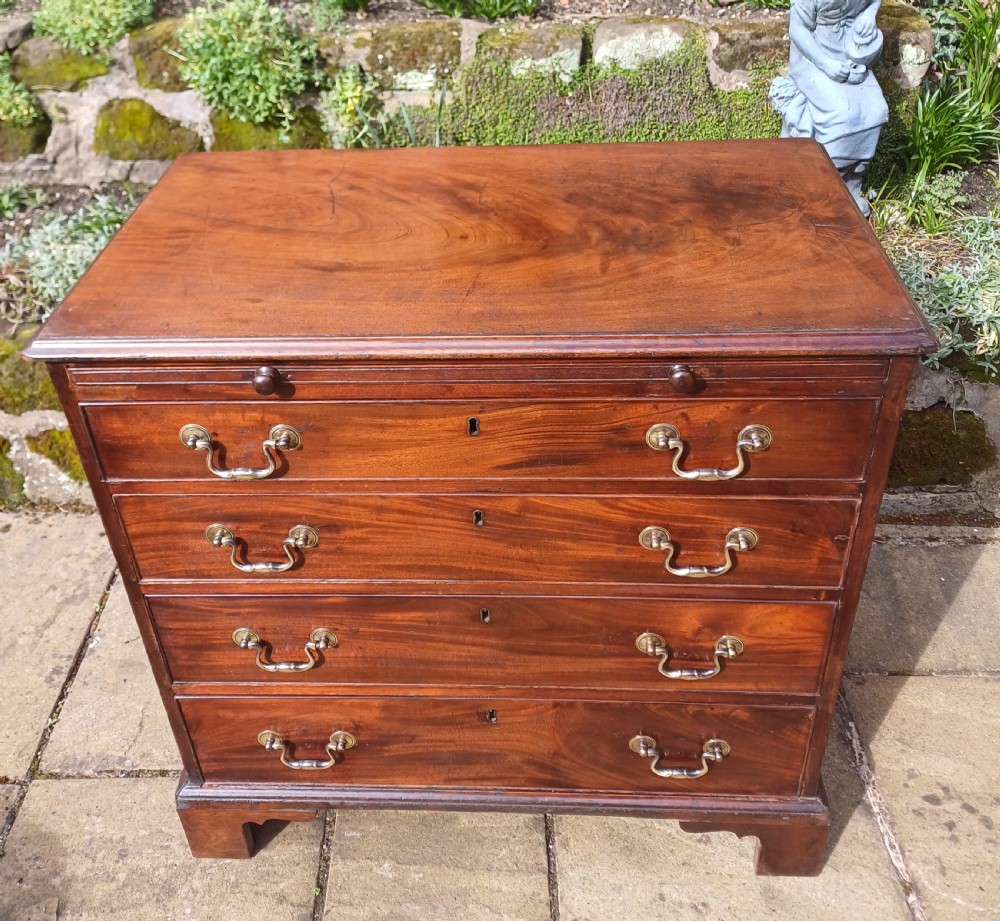 A small Georgian mahogany chest of drawers featuring four graduated drawers, brass swan-neck handles, a pull-out brushing slide, and bracket feet. View II