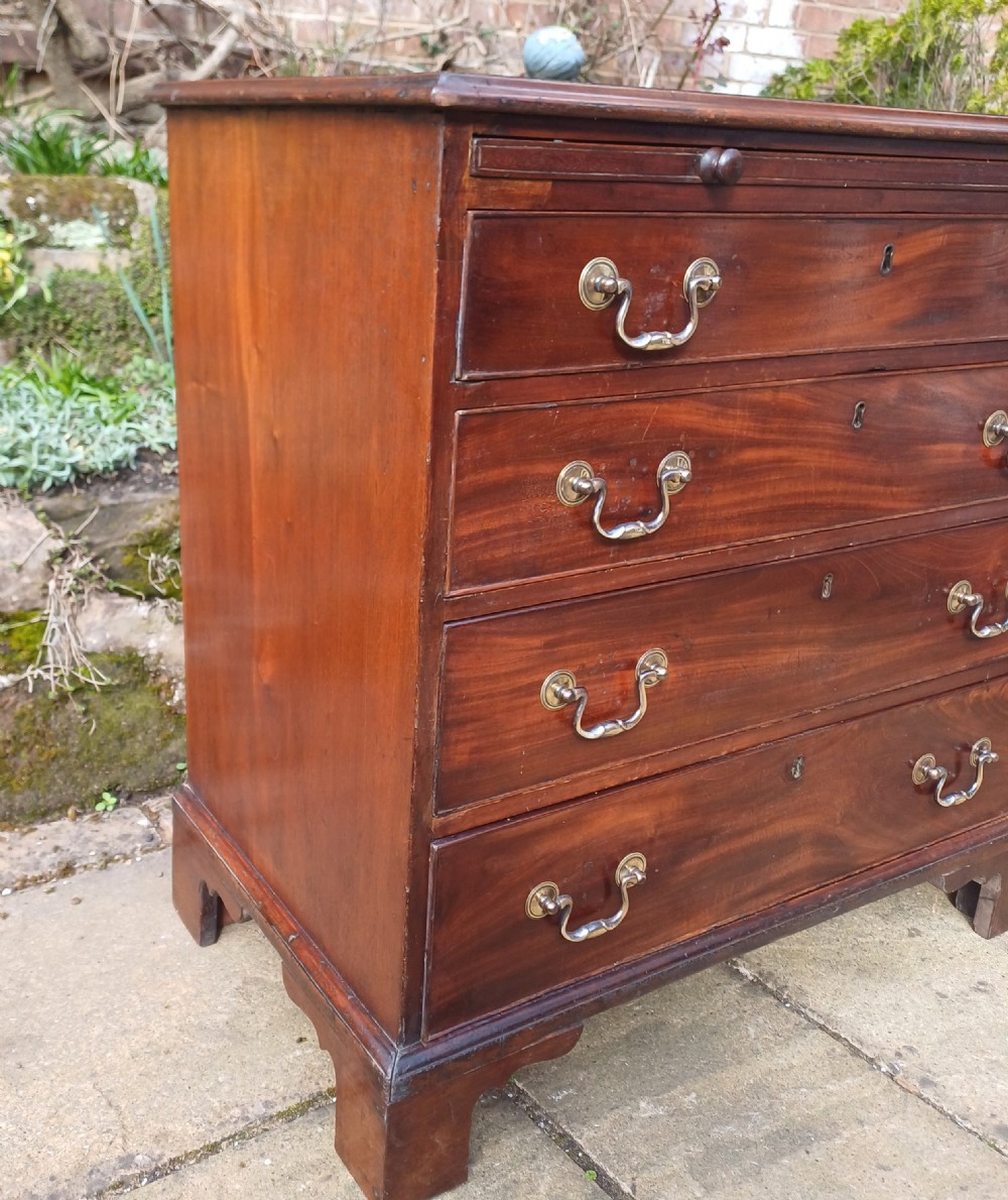 A small Georgian mahogany chest of drawers featuring four graduated drawers, brass swan-neck handles, a pull-out brushing slide, and bracket feet. View VII