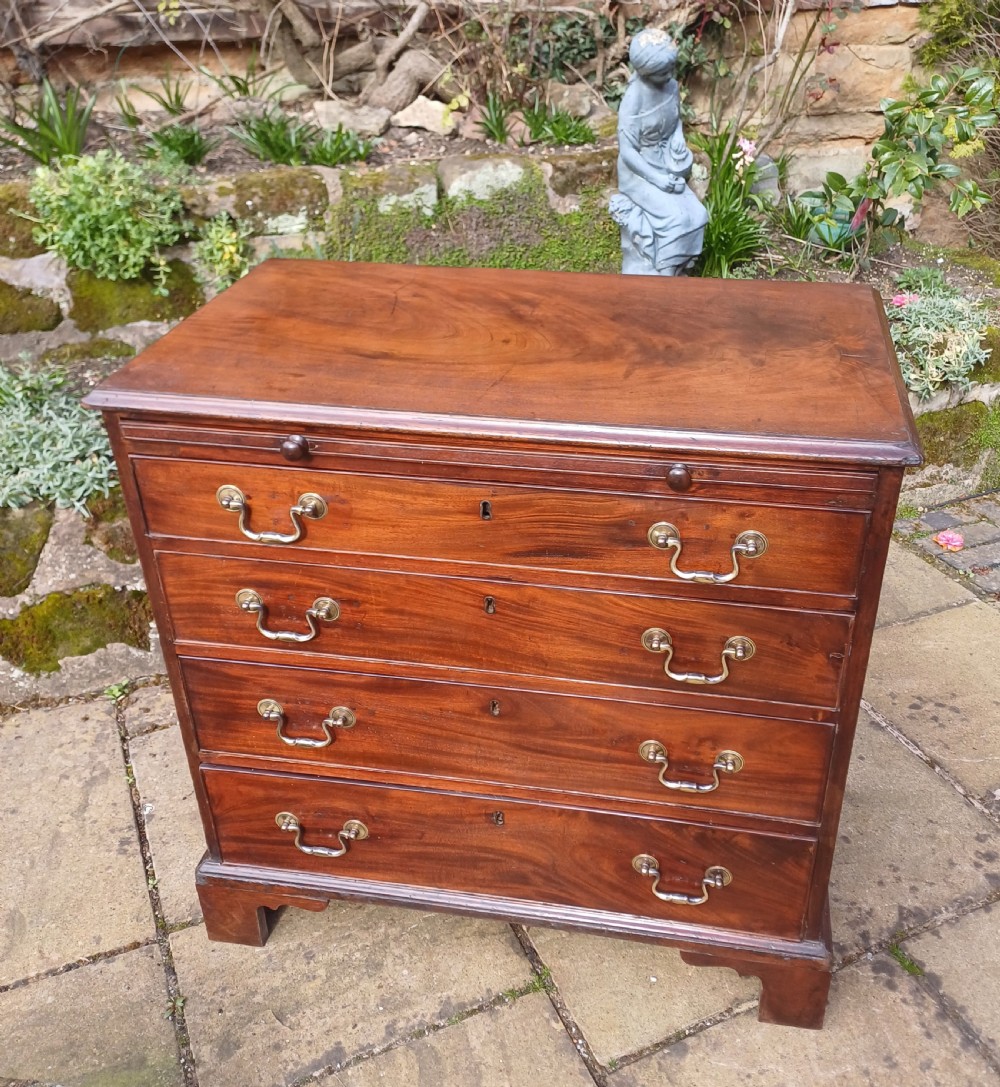 A small Georgian mahogany chest of drawers featuring four graduated drawers, brass swan-neck handles, a pull-out brushing slide, and bracket feet. View IX